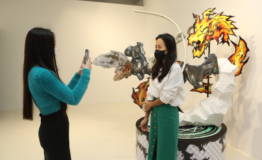 롯데백화점 잠실점 롯데갤러리에서 고객 2명이 뉴미디어 테임보우 전시회에서 작품을 배경으로 기념사진을 찍고 있다. 롯데백화점 제공